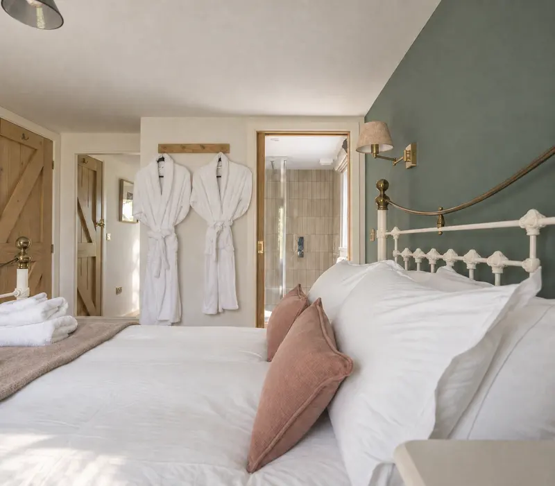 Bed with white linen and cushions beside an oak wardrobe