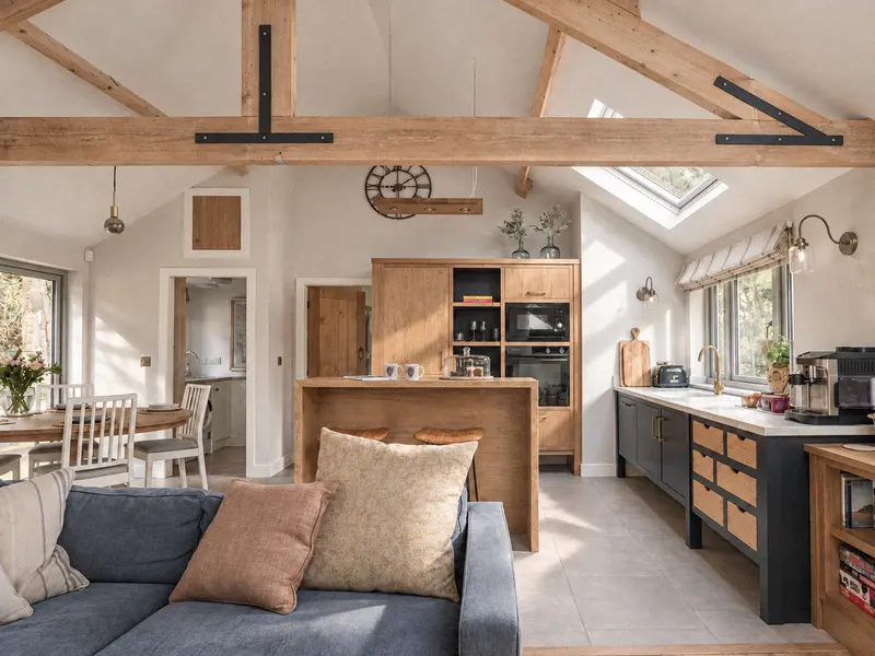 Open-plan living space and kitchen beneath exposed timber trusses